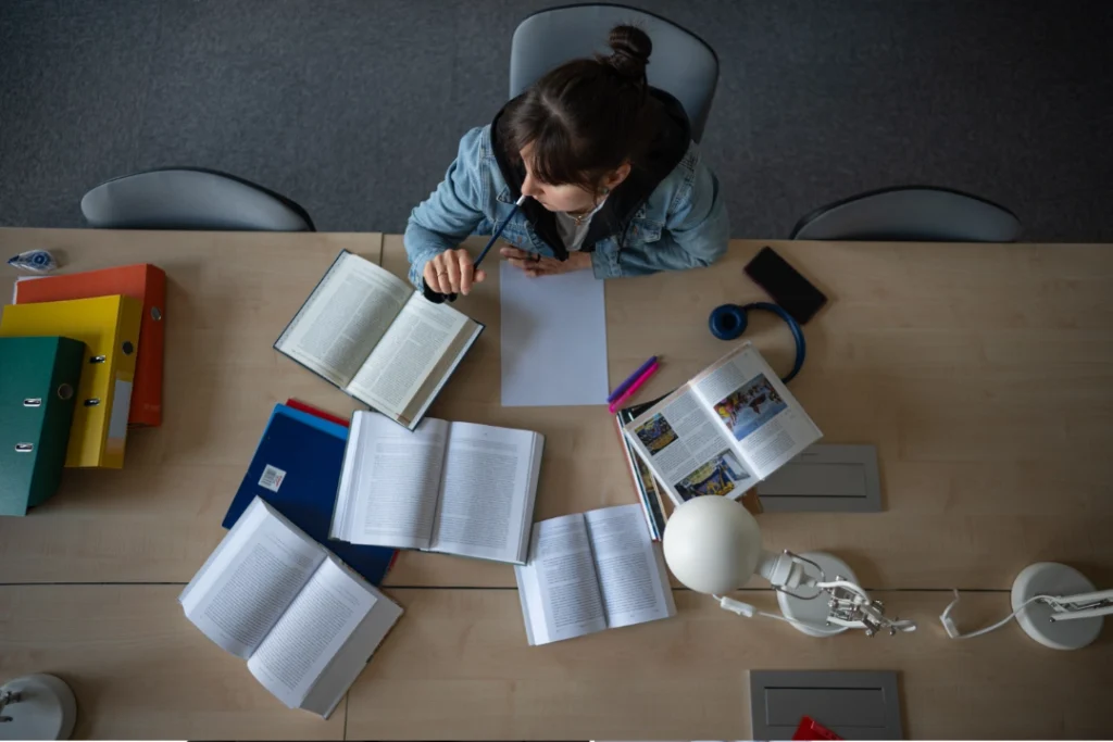Estudiante universitaria revisando materiales académicos desde casa.